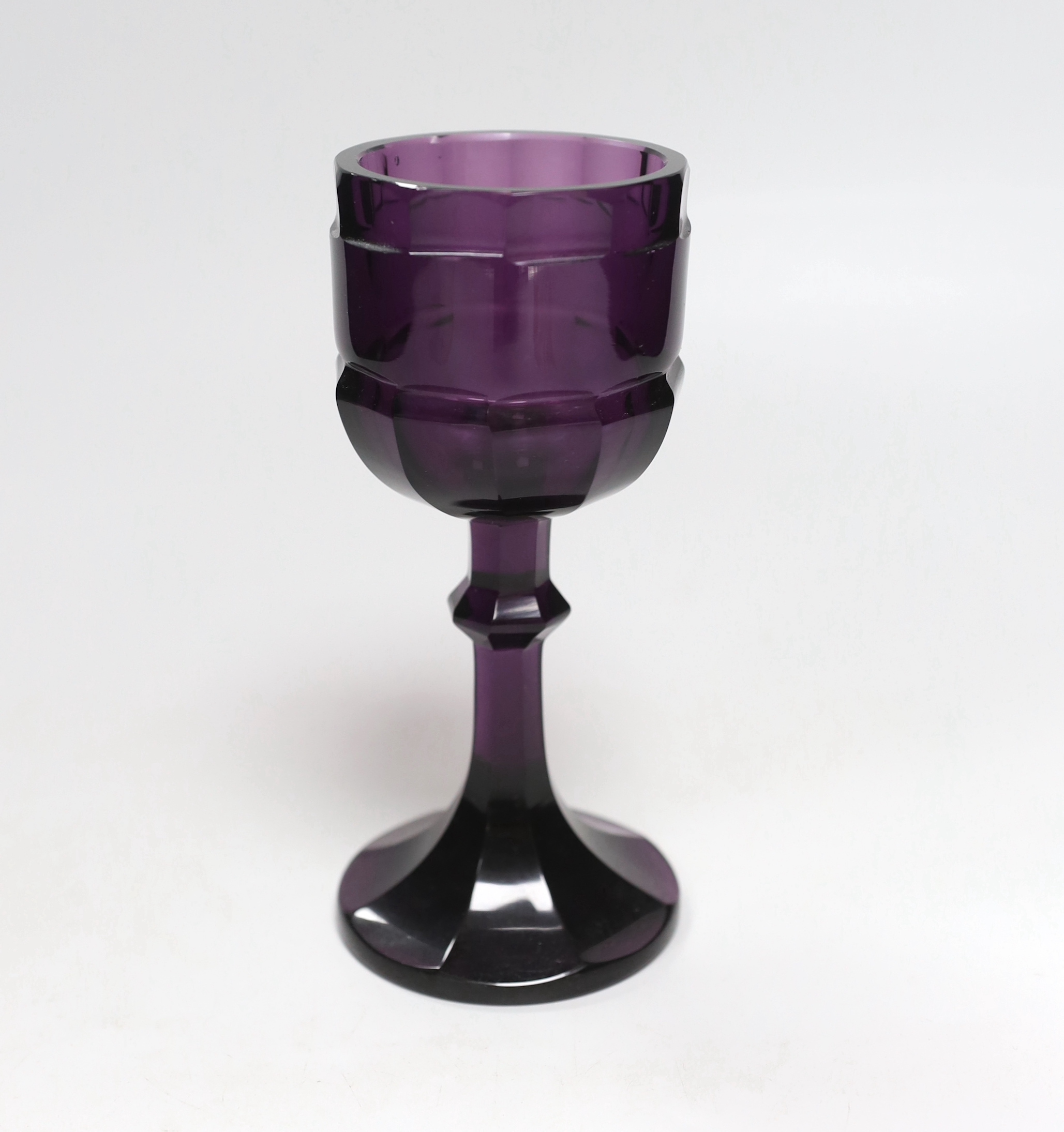 A Bohemian amethyst goblet, seemingly cut from a single piece of glass in a facetted form with a knopped stem cascading to a facetted foot with flat base and ground pontil, 17.5cm, weight 488 grams